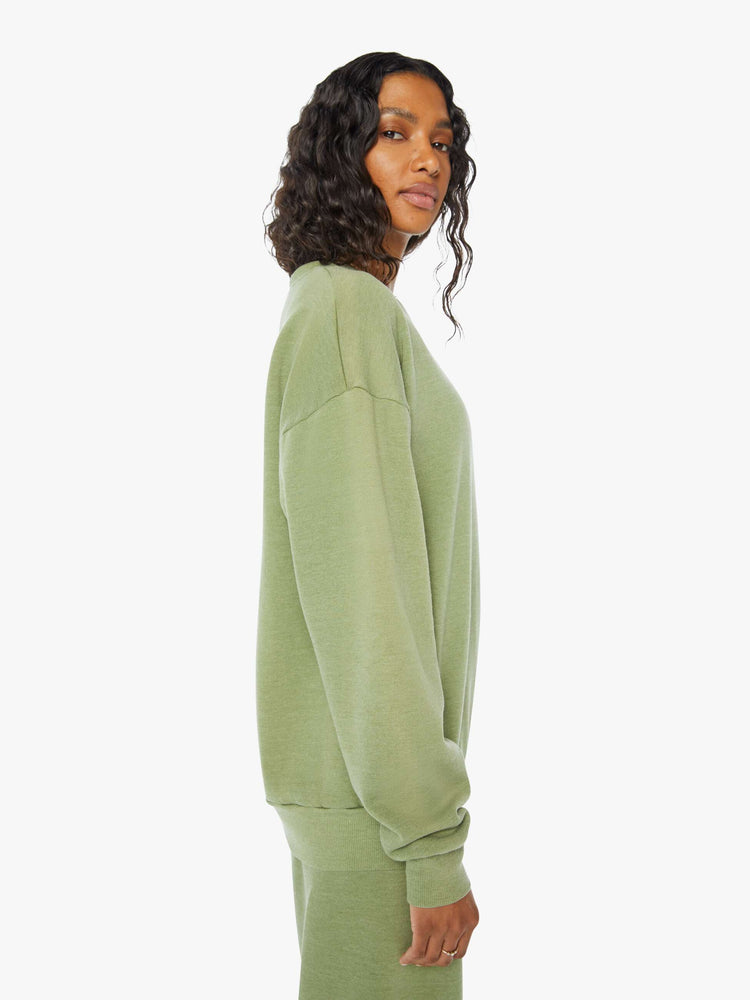 Side view of a  womens green crew neck sweatshirt featuring a relaxed fit and SPRWMN printed on the chest.