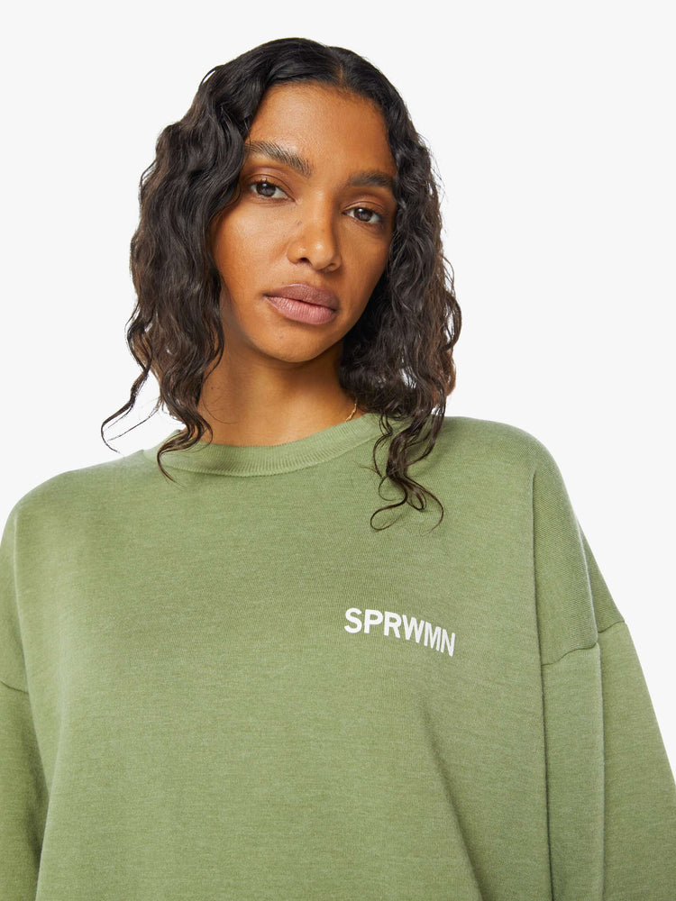 Front close up view of a  womens green crew neck sweatshirt featuring a relaxed fit and SPRWMN printed on the chest.