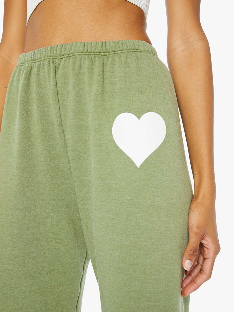 Front close up view of a womens green sweatpant featuring an elastic waist and a white heart printed on the hip.