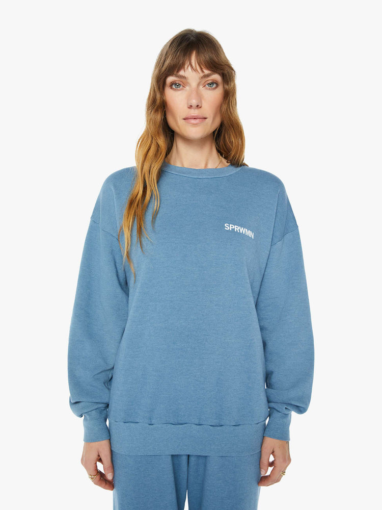 Front view of a  womens blue crew neck sweatshirt featuring a relaxed fit and SPRWMN printed on the chest.