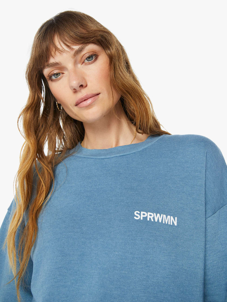 Front close up view of a  womens blue crew neck sweatshirt featuring a relaxed fit and SPRWMN printed on the chest.