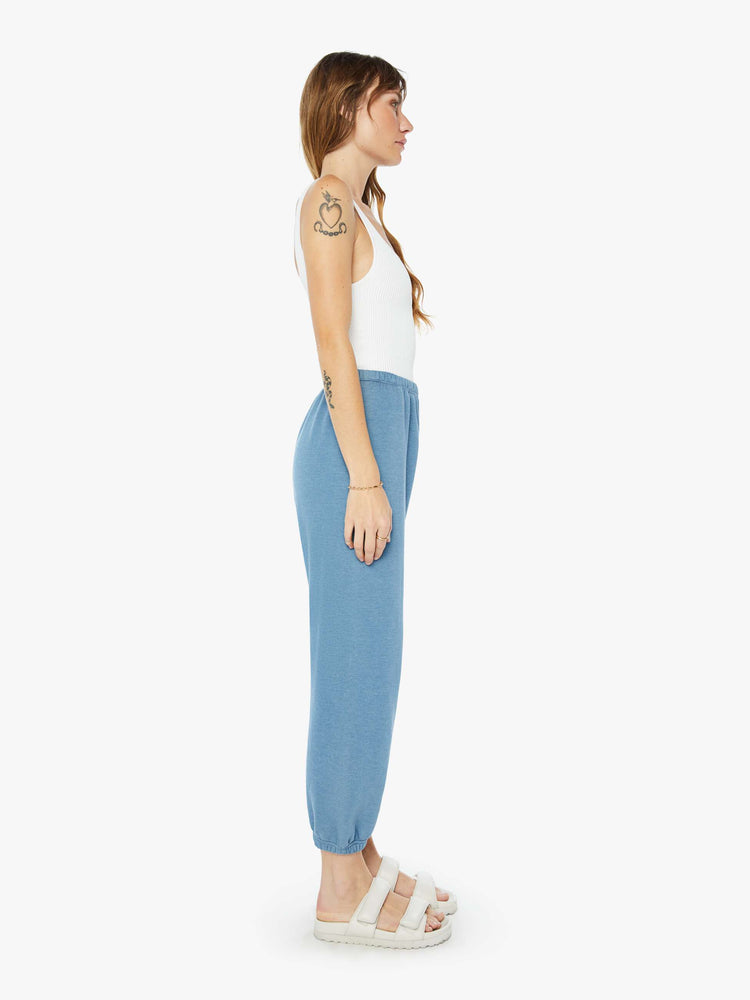 Side view of a womens blue sweatpant featuring an elastic waist and a white heart printed on the hip.