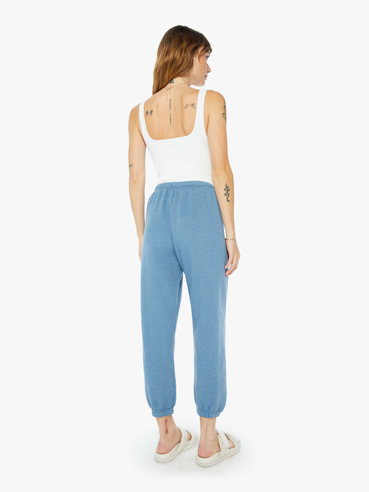 Back view of a womens blue sweatpant featuring an elastic waist and a white heart printed on the hip.