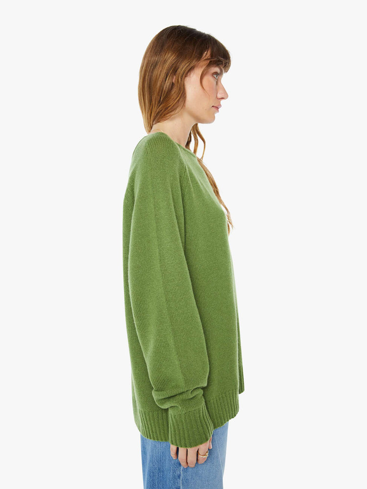 Side view of a  womens green crew neck knit sweater featuring an oversized fit.