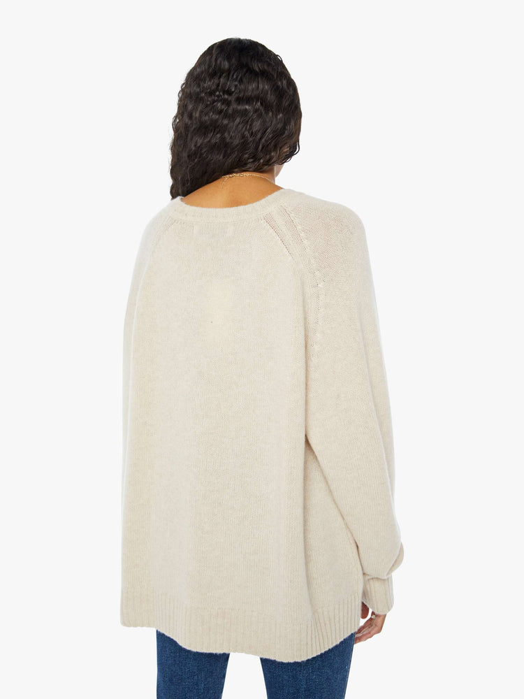 Back view of a  womens beige crew neck knit sweater featuring an oversized fit.
