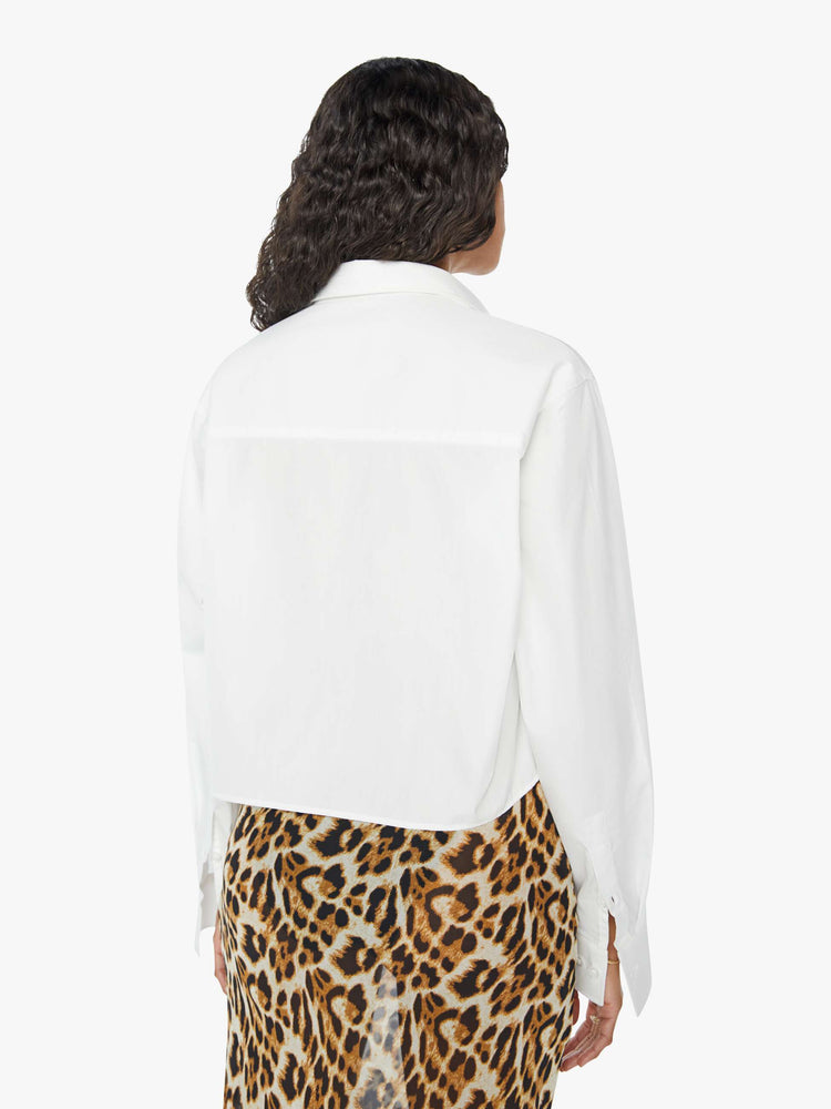 Back view of a womens white button down shirt featuring a cropped hem and chest pocket.