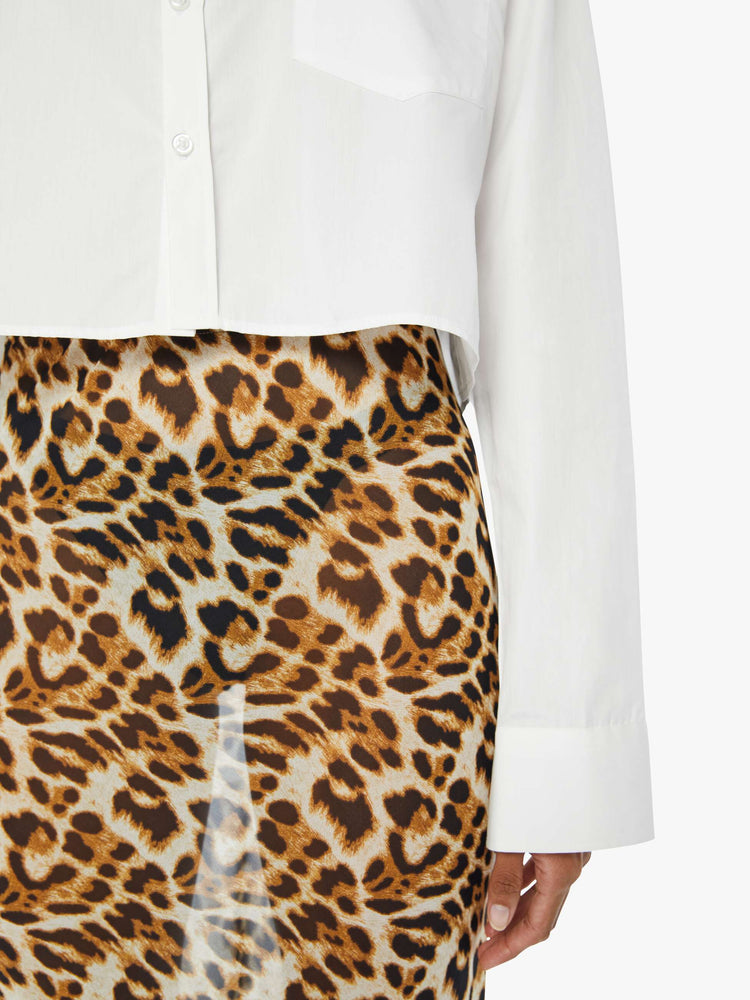 Front close up view of a womens white button down shirt featuring a cropped hem and chest pocket.