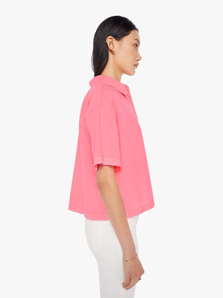 Side view of a womens neon pink collar shirt featuring a 3/4 length button, dropped short sleeves, and a cropped boxy fit.