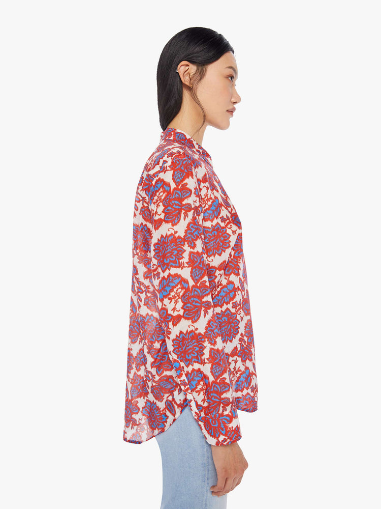 Side view of a woman wearing a red, white, and blue floral button up shirt with long sleeves