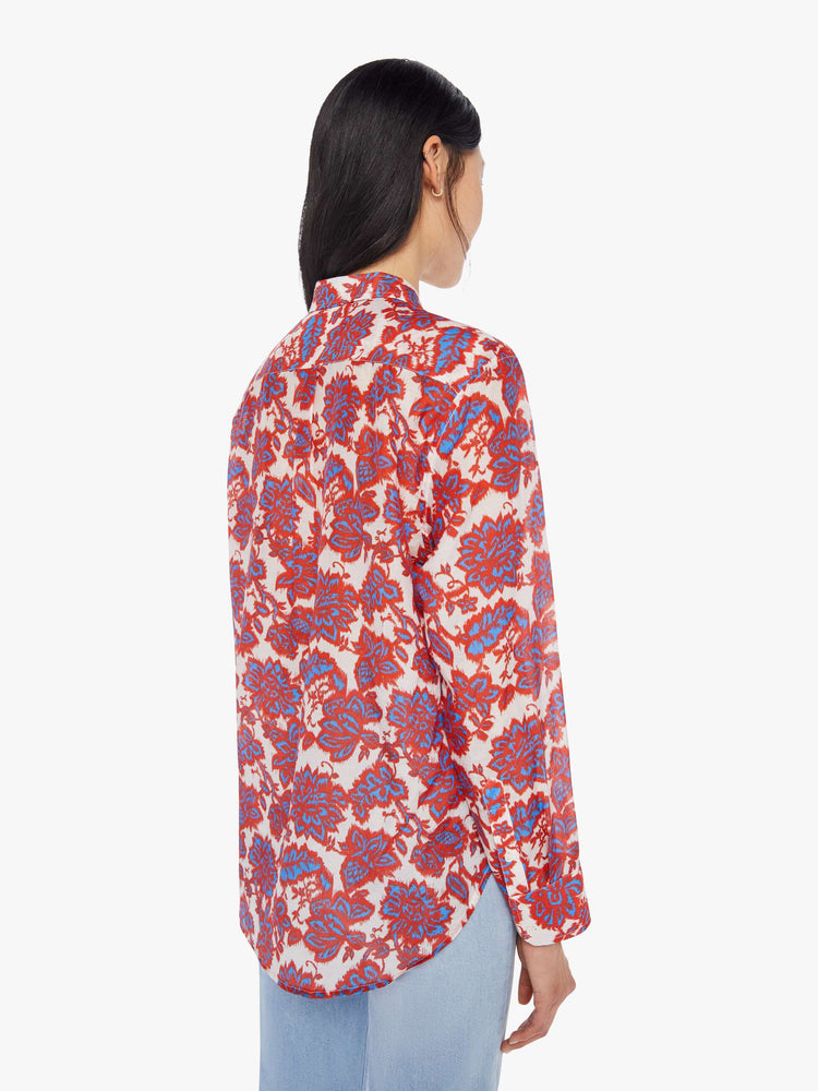 Back view of a woman wearing a red, white, and blue floral button up shirt with long sleeves