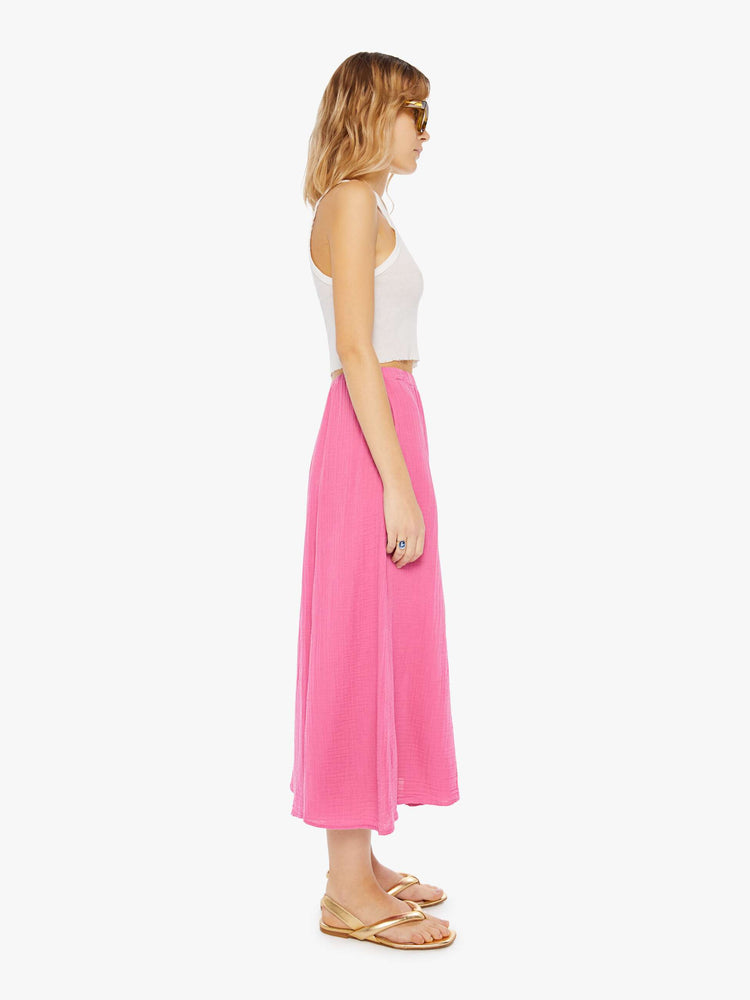 Side view of a woman wearing a pink, calf-length skirt with elastic waistband