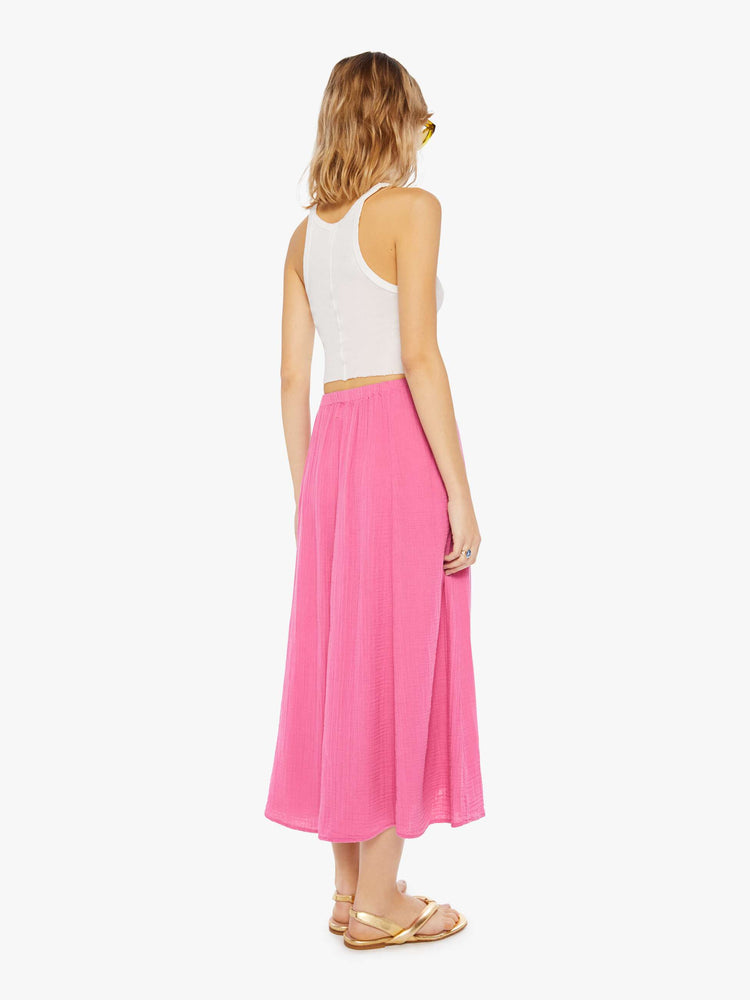 Back view of a woman wearing a pink, calf-length skirt with elastic waistband