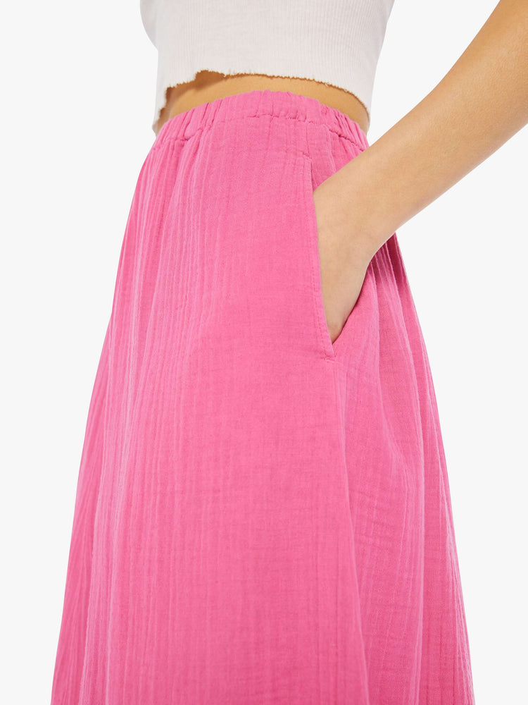 Detail view of a woman wearing a pink, calf-length skirt with elastic waistband