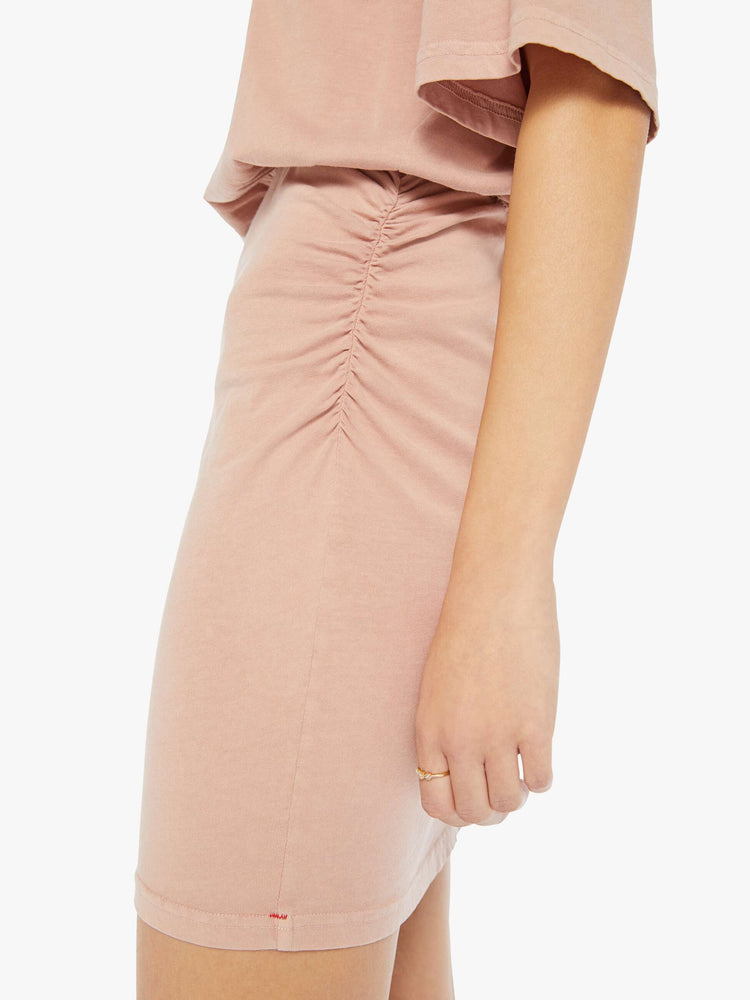 Detail view of a woman wearing a pink t-shirt dress with an elastic waistband and ruched skirt