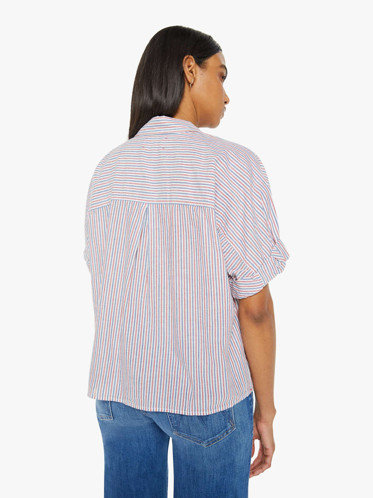 Back view of a woman short-sleeve button-downin red, white and blue stripes with a collared neck, drop shoulders, short sleeves with a rolled hem and a boxy fit.