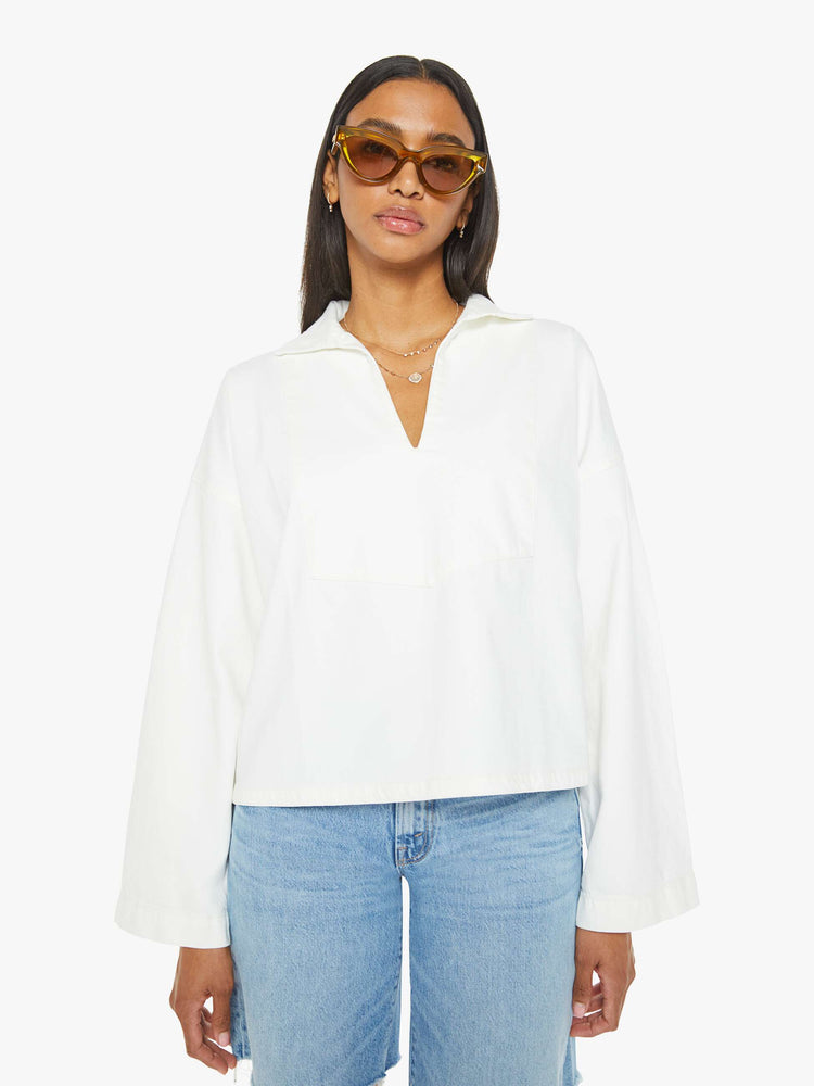 Front view of a woman white long sleeve blouse with a collared V-neck, drop shoulders, loose long sleeves and a boxy fit.