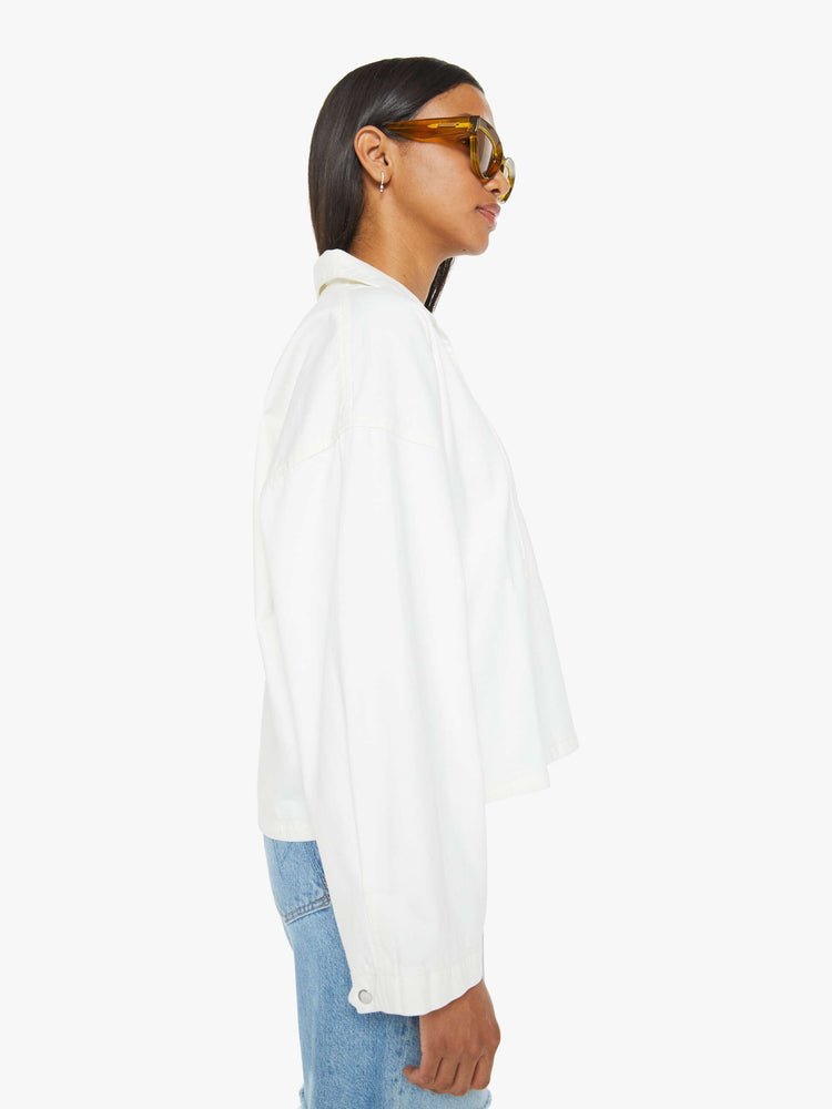 Side view of a woman white long sleeve blouse with a collared V-neck, drop shoulders, loose long sleeves and a boxy fit.