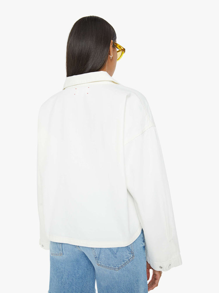 Back view of a woman white long sleeve blouse with a collared V-neck, drop shoulders, loose long sleeves and a boxy fit.