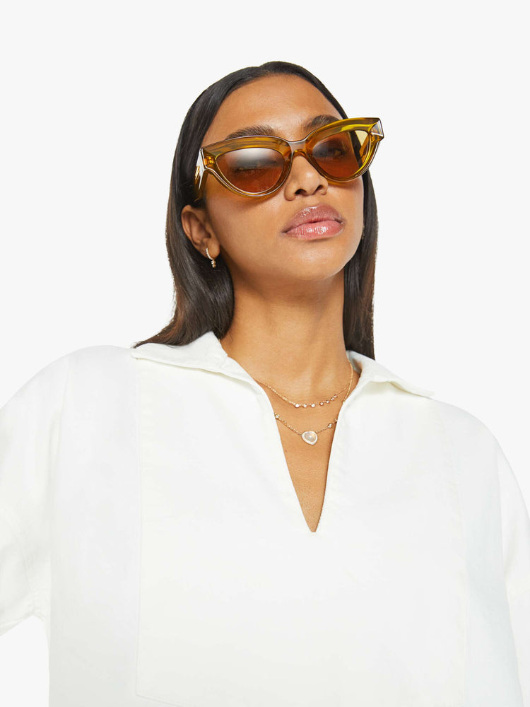 Close up view of a woman white long sleeve blouse with a collared V-neck, drop shoulders, loose long sleeves and a boxy fit.