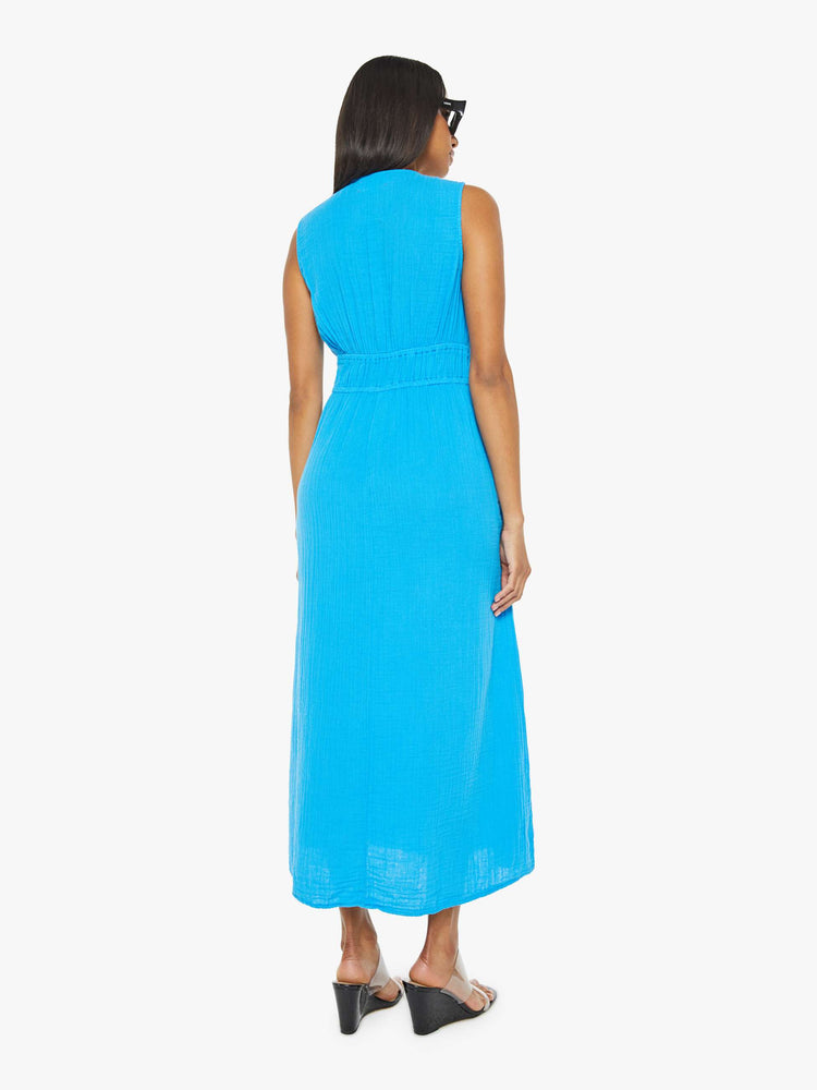Back view of a woman sleeveless dress in blue, the Arwen dress features a V-neck, gathered, angled seams at the chest and a loose calf-length skirt.