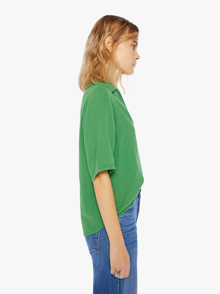 Side view of a womens green top featuring a v neck collar, 3/4 short sleeves, and a boxy cropped fit.