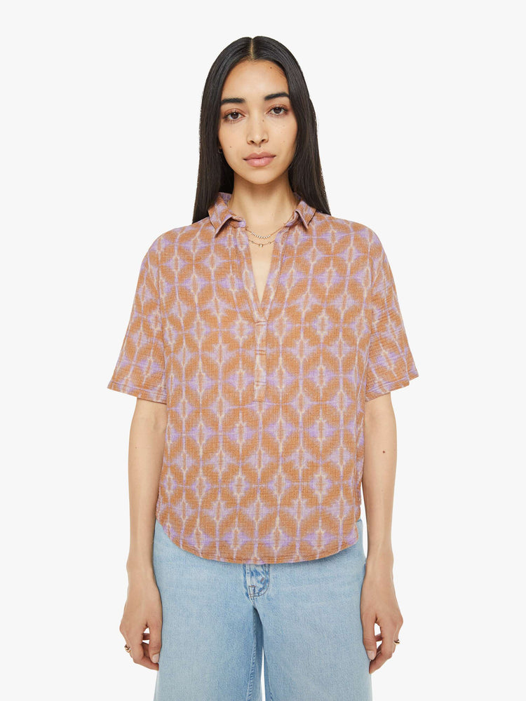 Front view of a woman collared blouse in a terracotta and lavender geometric print, the top is designed with a V-neck, drop shoulders, oversized short sleeves and loose, slightly boxy fit.