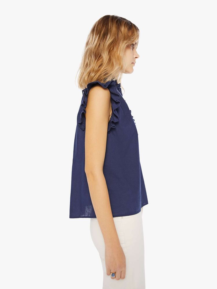 Side view of a navy blue blouse featuring a ruffled mock neck and sleeveless ruffles.