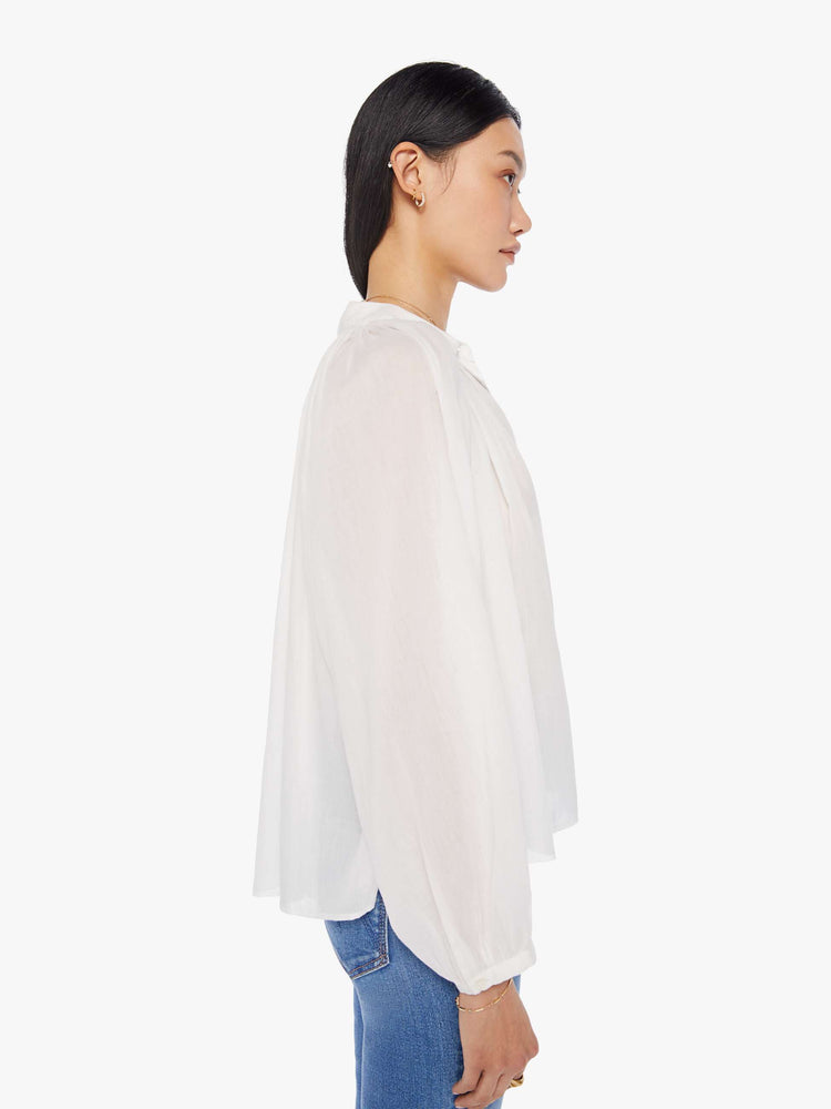 Side view of a womens white button down blouse featuring pleated shoulder details and balloon long sleeves.