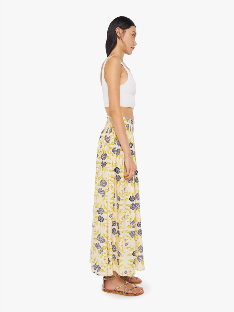 Side view of a woman wearing a long, off-white skirt with blue floral print and elastic waistband