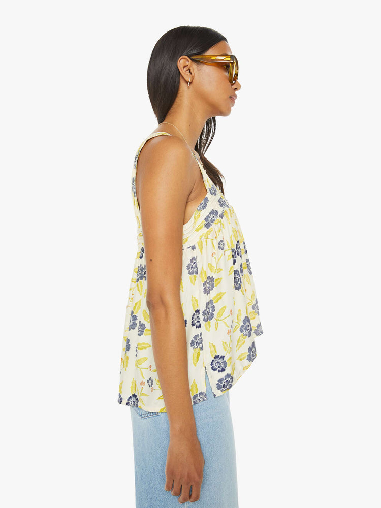 Side view of a woman top in a pale yellow, indigo and white floral print, and features detailed straps and buttons in the back.