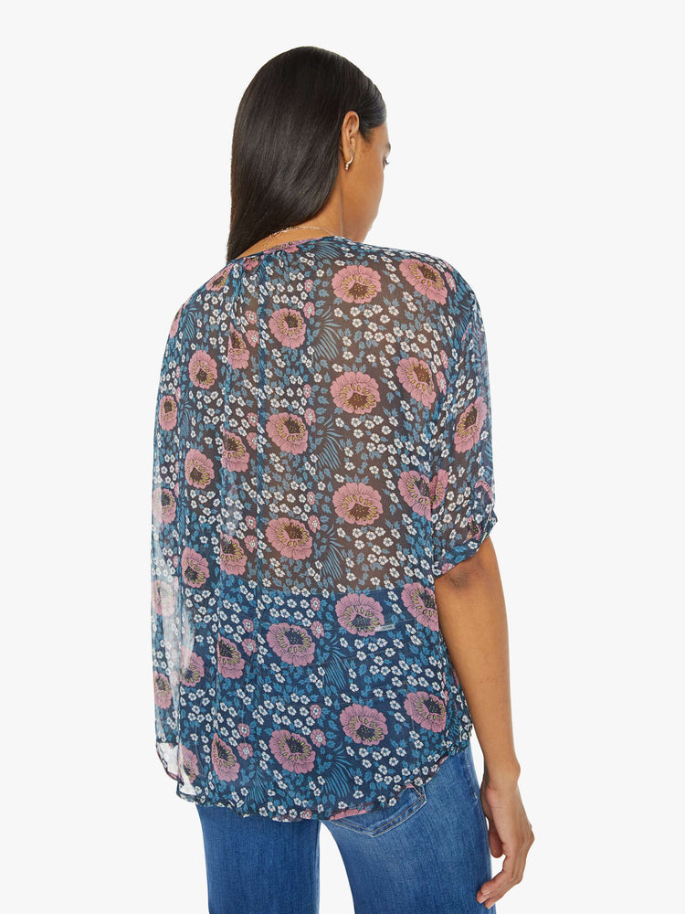 Back view of a woman top in dark teal with a pink and white vintage-inspired floral print, and features a deep V-neck, drop shoulders, elbow-length sleeves, a curved hem and a loose, flowy fit.