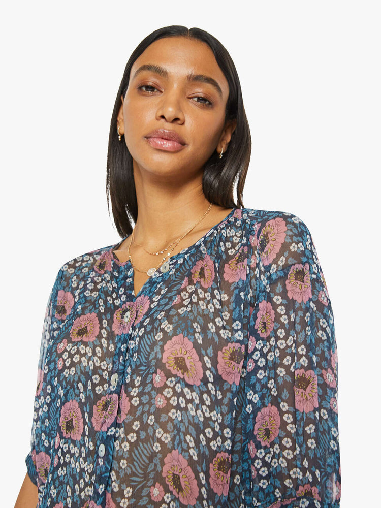 Close up view of a woman top in dark teal with a pink and white vintage-inspired floral print, and features a deep V-neck, drop shoulders, elbow-length sleeves, a curved hem and a loose, flowy fit.