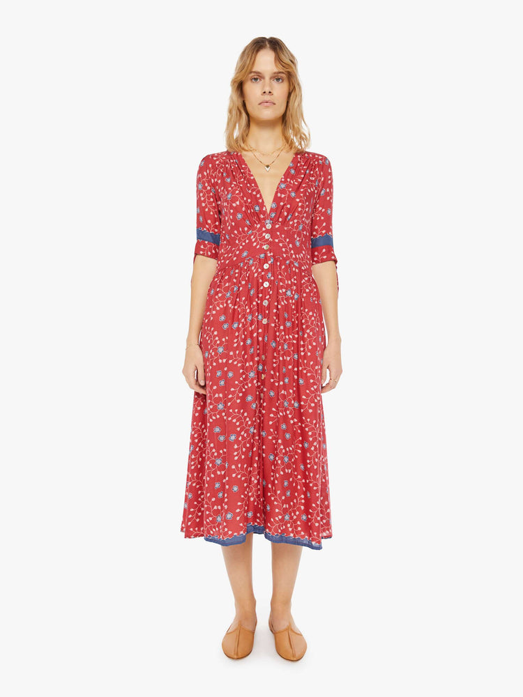 Front view of a woman wearing a red button up dress with blue floral print and elbow length sleeves
