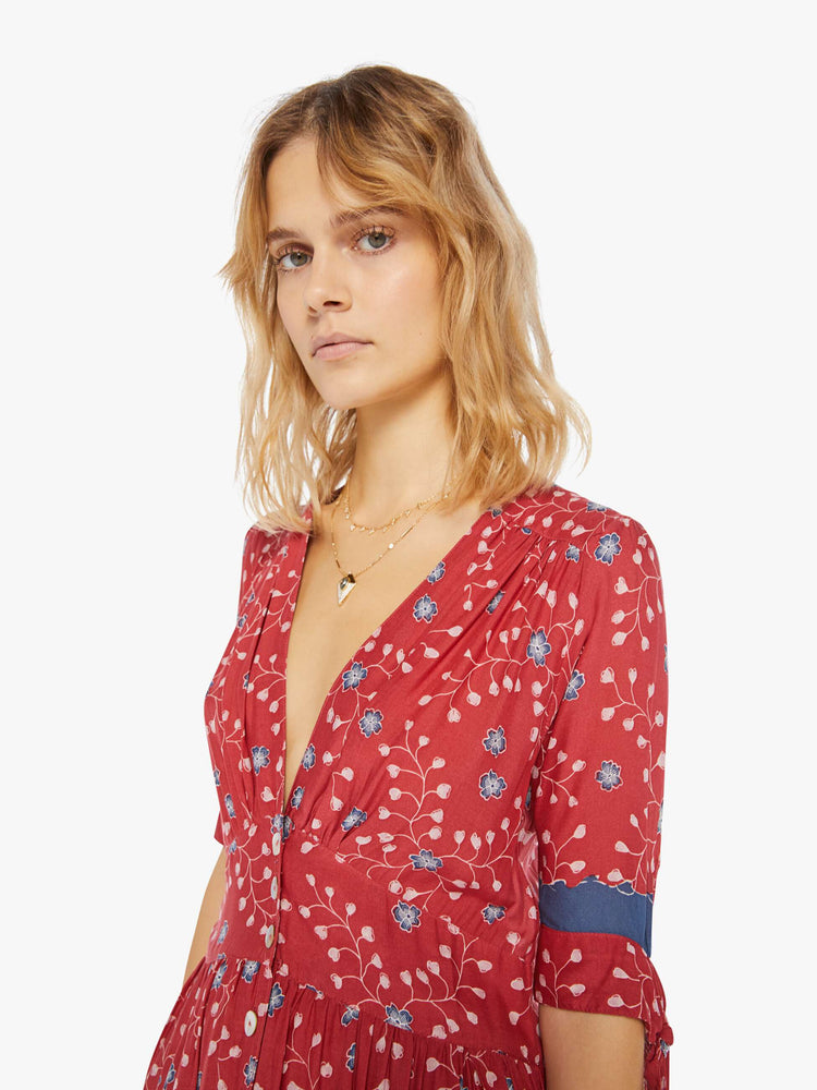 Detail view of a woman wearing a red button up dress with blue floral print and elbow length sleeves
