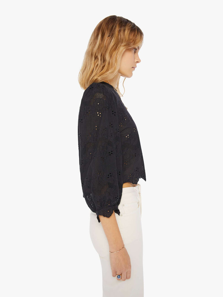 Side view of a woman wearing a black eyelet blouse with 3/4 balloon sleeves