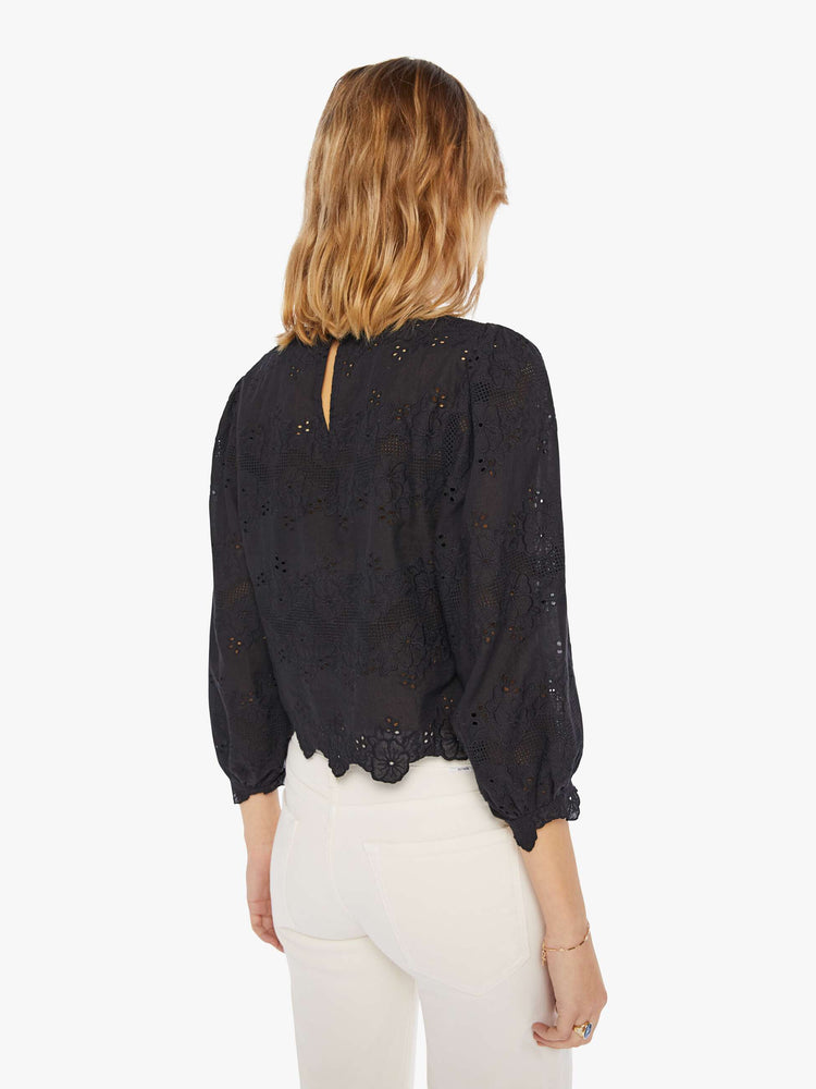 Back view of a woman wearing a black eyelet blouse with 3/4 balloon sleeves