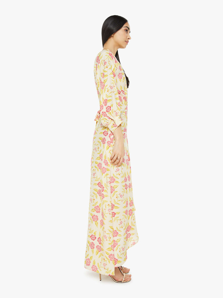 Side view of a woman long sleeve dress is made from 100% silk in a tropical floral print, and features a V-neck, tied waist and long maxi skirt with a loose, flowy fit.
