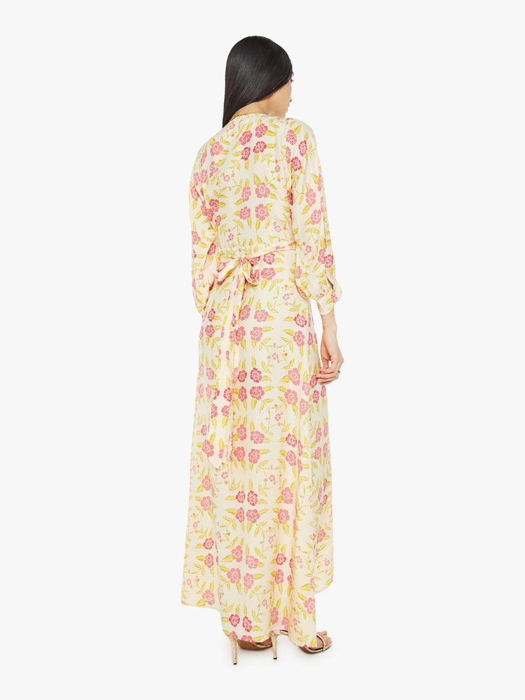 Back view of a woman long sleeve dress is made from 100% silk in a tropical floral print, and features a V-neck, tied waist and long maxi skirt with a loose, flowy fit.
