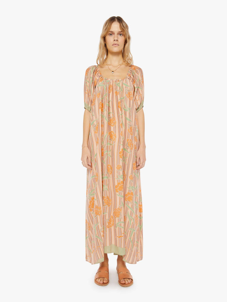 front view of a woman in a cream maxi dress with stripes and a warm-toned floral print, designed with a scoop neck, elbow-length sleeves and an A-line cut for a loose, breezy feel.