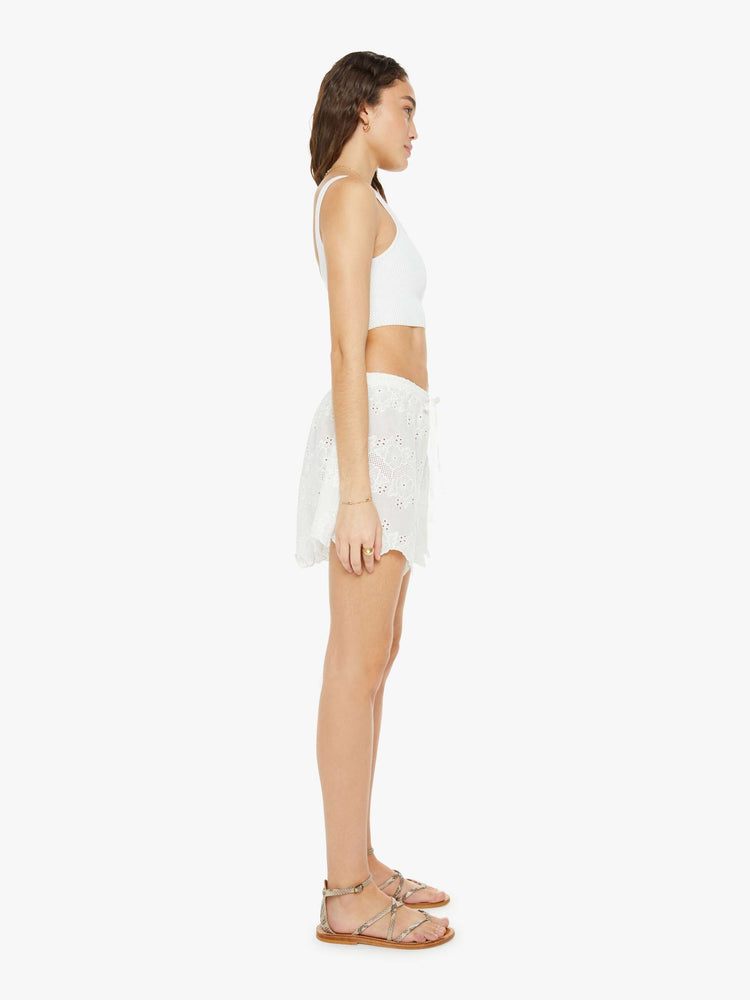 Side view of a woman white shorts are designed with an elastic high waist, side slit pockets, a slightly curved hem and a loose, flowy fit.