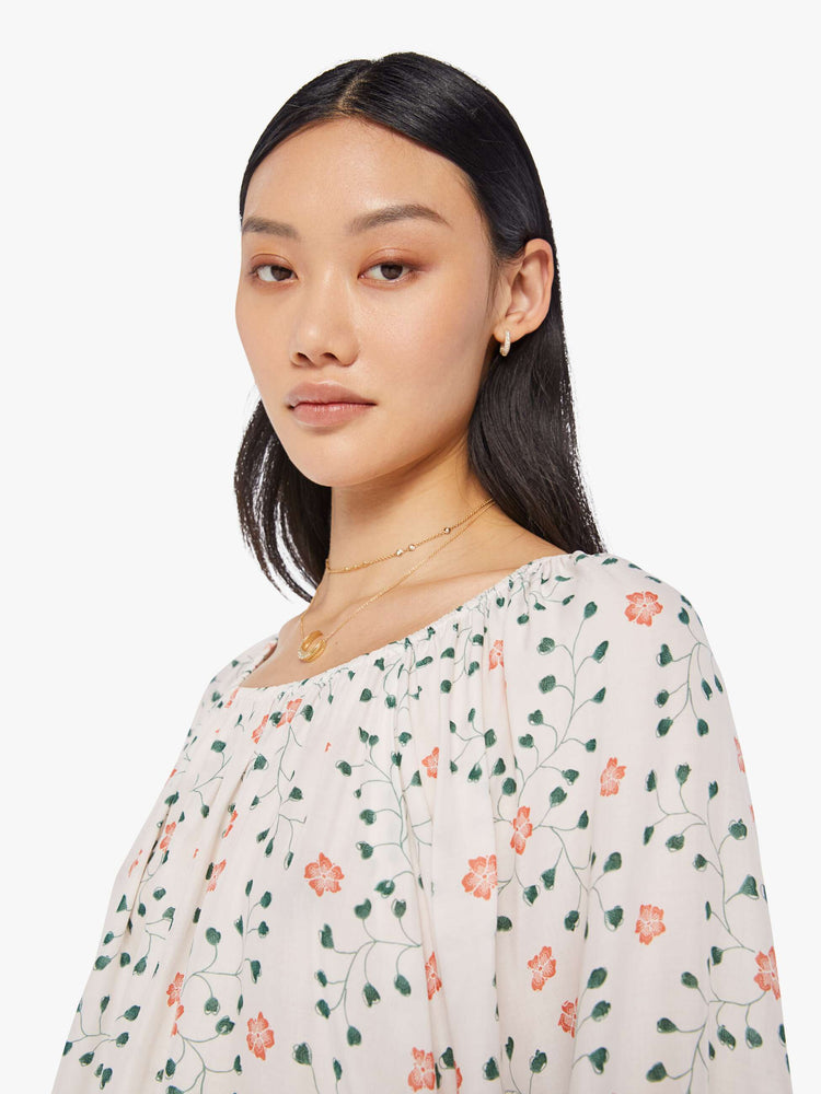 close up/swatch view of a woman in an off-white top with a colorful floral print and features an elastic boat neck that can be worn off-the-shoulder, 3/4-length balloon sleeves and a flowy fit.