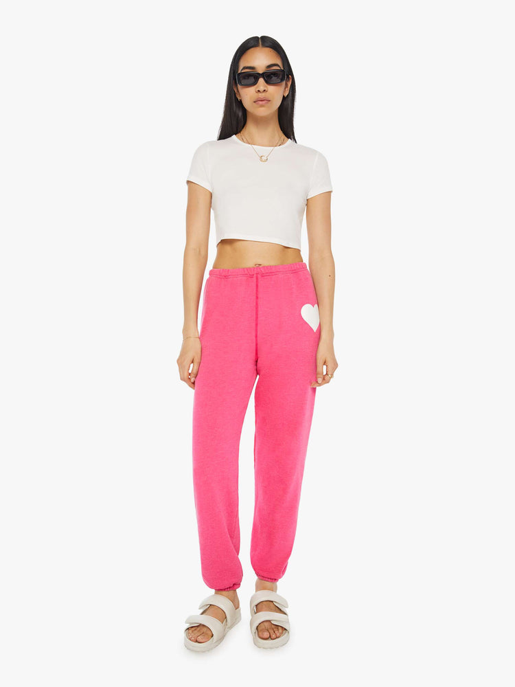 Front view of a womens hot pink sweatpant featuring a white heart graphic.