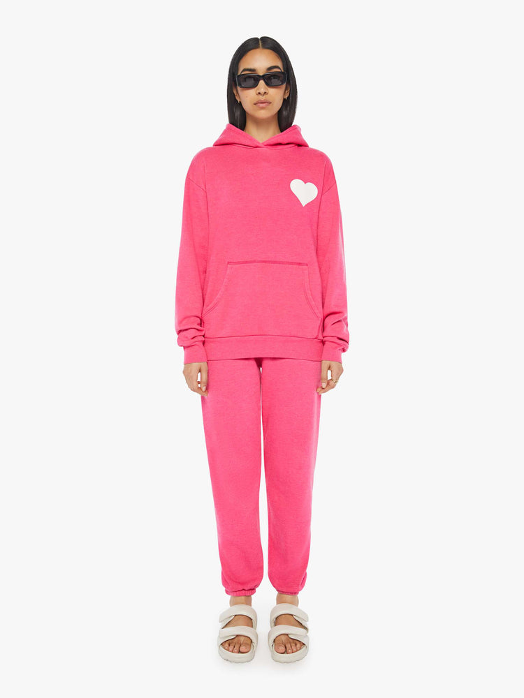 Front full body view of a womens matching hoodie and sweatpant in hot pink featuring a white heart graphic.