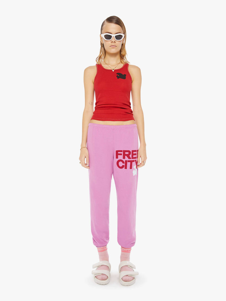 Front view of a woman wearing pink sweatpants and a red tank.
