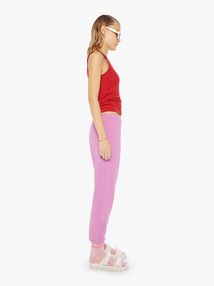 Side view of a woman wearing pink sweatpants and a red tank.