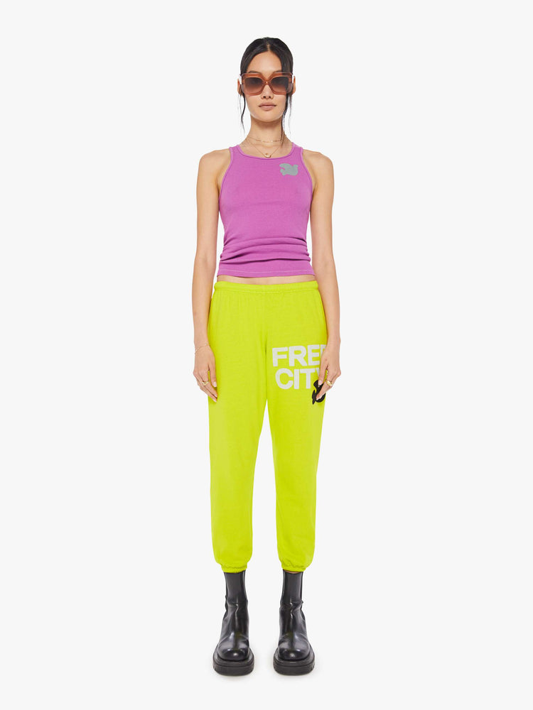 Front view of a woman wearing neon yellow sweatpants and a bright purple tank.