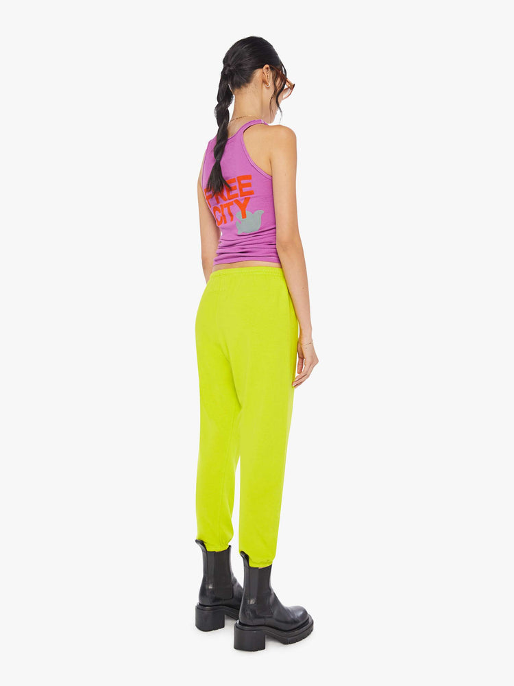 Back view of a woman wearing neon yellow sweatpants and a bright purple tank.