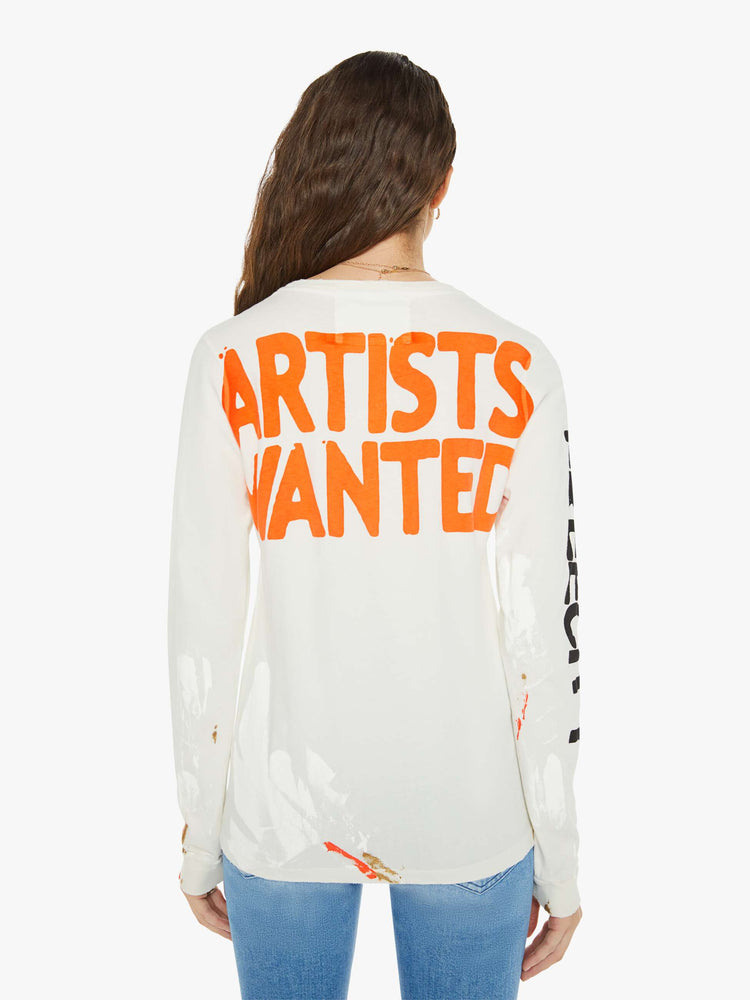 Back view of a woman in a white long sleeve with a crewneck, oversized fit, the brand's logo down the arms and a text graphic on the back.
