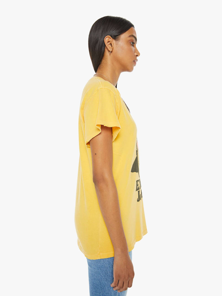 Side view of woman in a yellow tee in golden-yellow, the tee honors Elton John with a graphic portrait on the front.