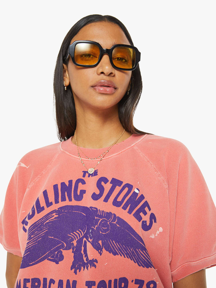 Close up view of a woman short sleeve sweatshirt in red, the sweatshirt pays homage to The Rolling Stones' 1978 tour with a faded text graphic in navy on the front.